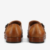 A rear view of a pair of tan leather dress shoes with brown wooden soles, featuring a double buckle design.