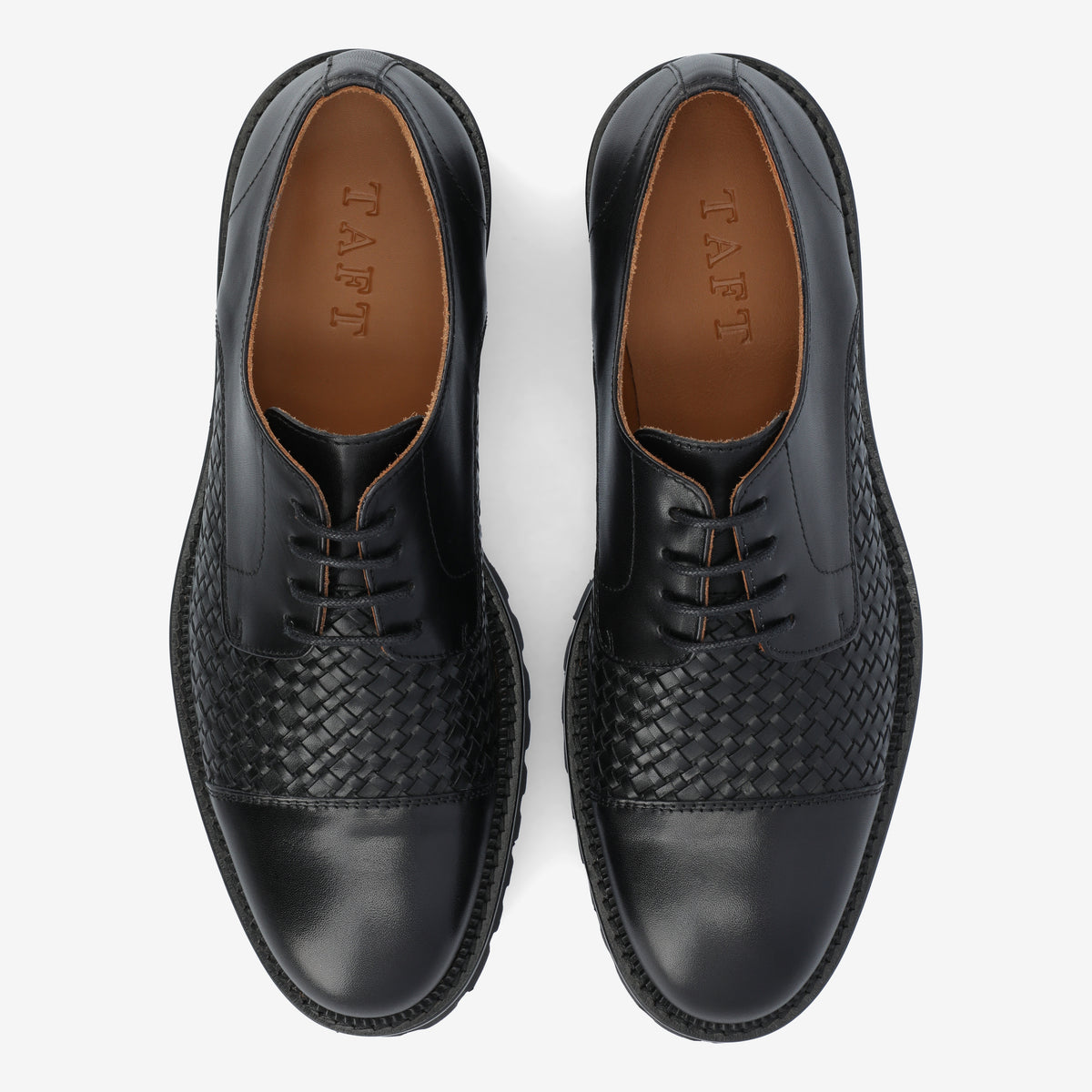 A pair of black leather dress shoes with brown insoles, featuring a woven pattern on the midsection and TAFT embossed on the inner soles.