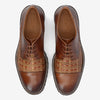 Top view of a pair of brown leather dress shoes with woven detailing across the midsection and TAFT embossed on the insoles.