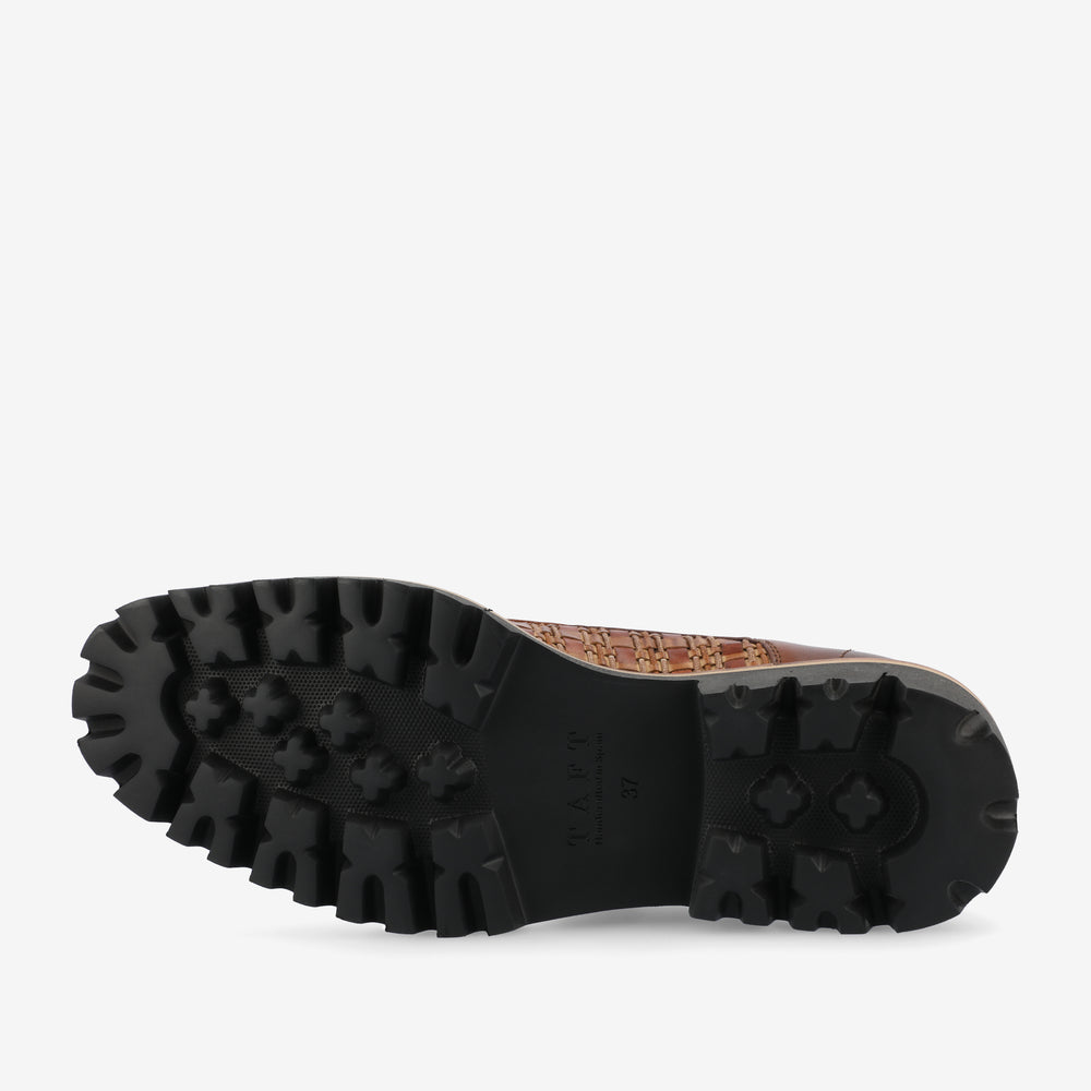 The image shows the sole of a shoe with a rugged, textured tread pattern. The shoe bottom is black with deep grooves for traction.