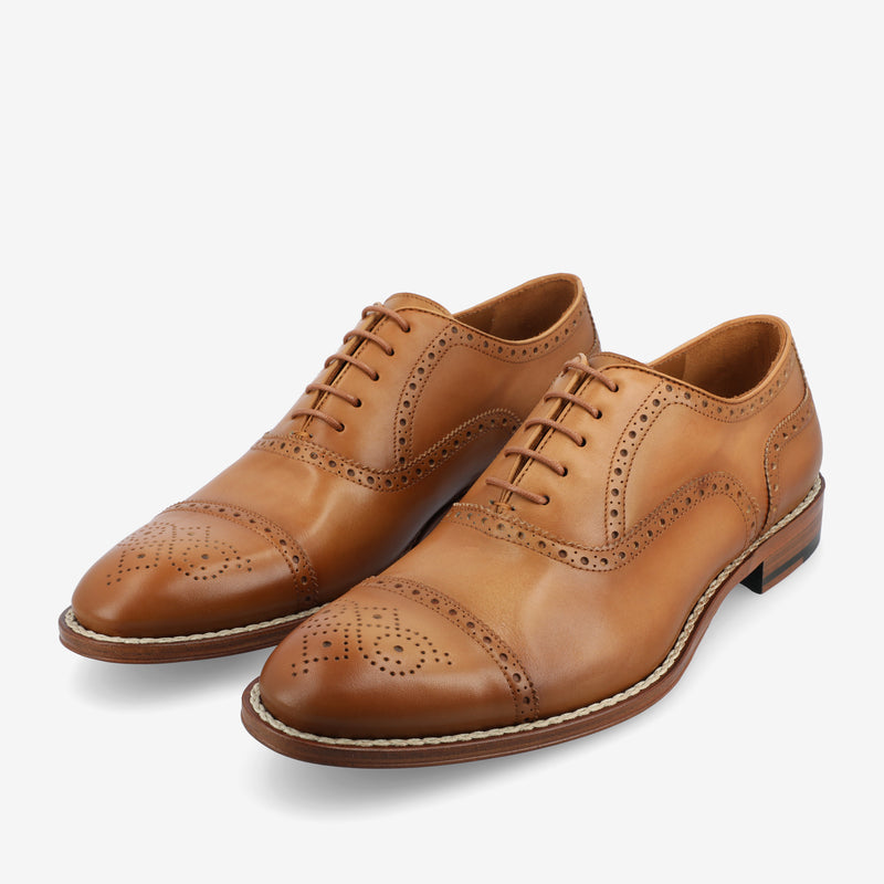 A pair of brown leather brogue oxford shoes with decorative perforations and laces.