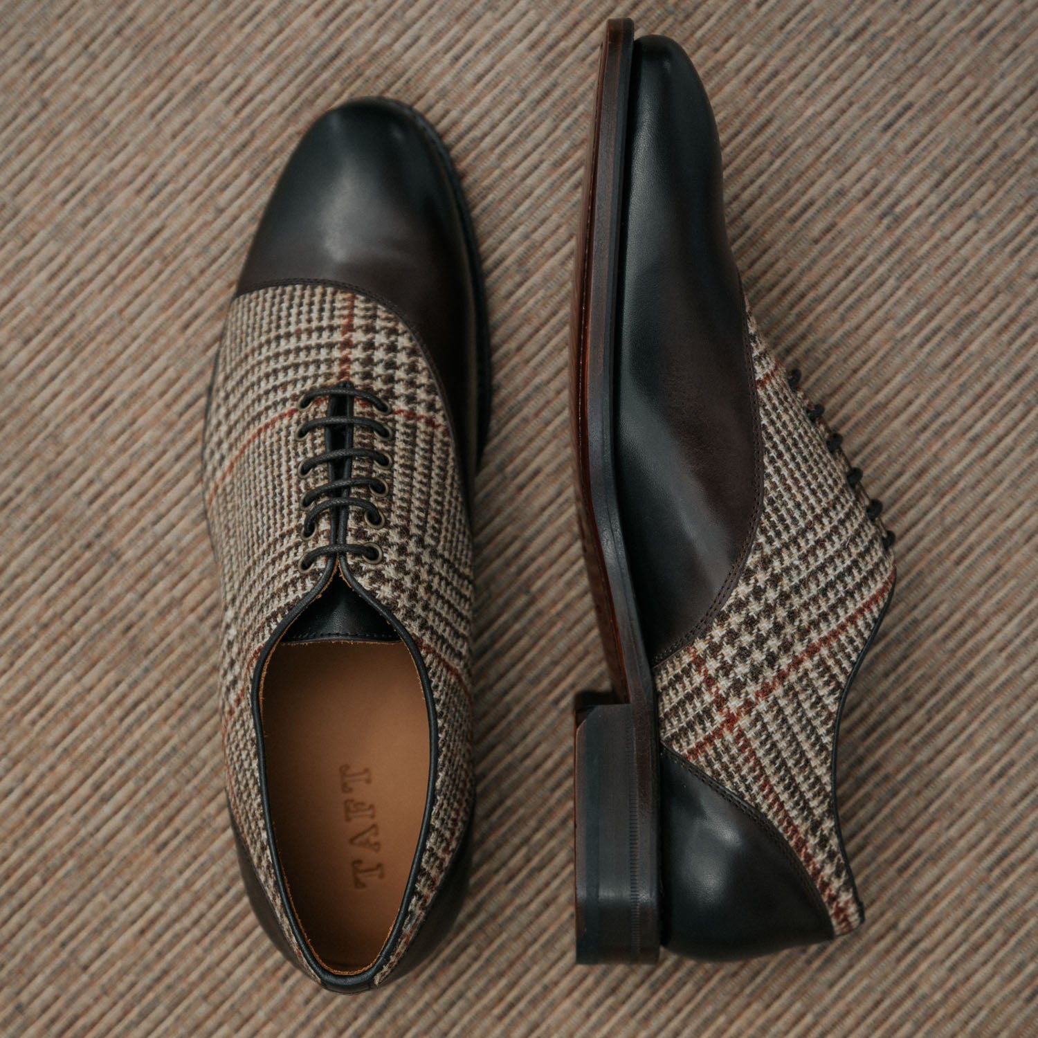 A pair of men's dress shoes with houndstooth fabric and dark leather details, shown from a top and side view on a textured surface.