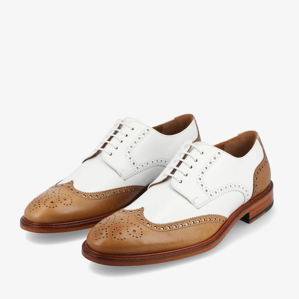 A pair of two-tone oxford shoes with white and brown leather, featuring brogue detailing and laces.