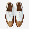 Pair of white and tan leather brogue dress shoes with perforated detailing and laces, viewed from above.