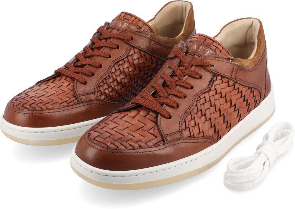 A pair of brown woven leather sneakers with white soles and brown laces, accompanied by an extra set of white laces.