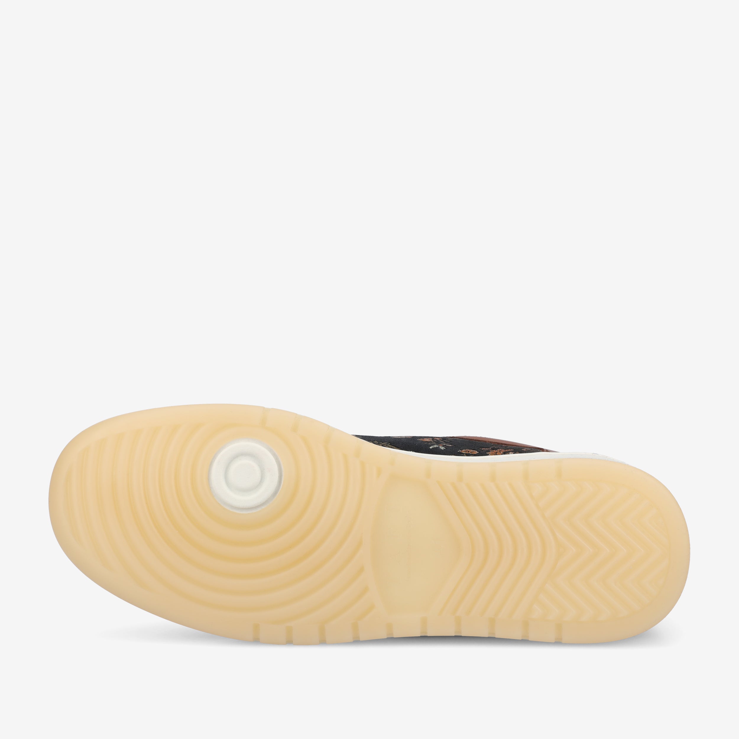 View of the outsole of a sneaker showing a mix of circular and zigzag tread patterns in a translucent beige color.