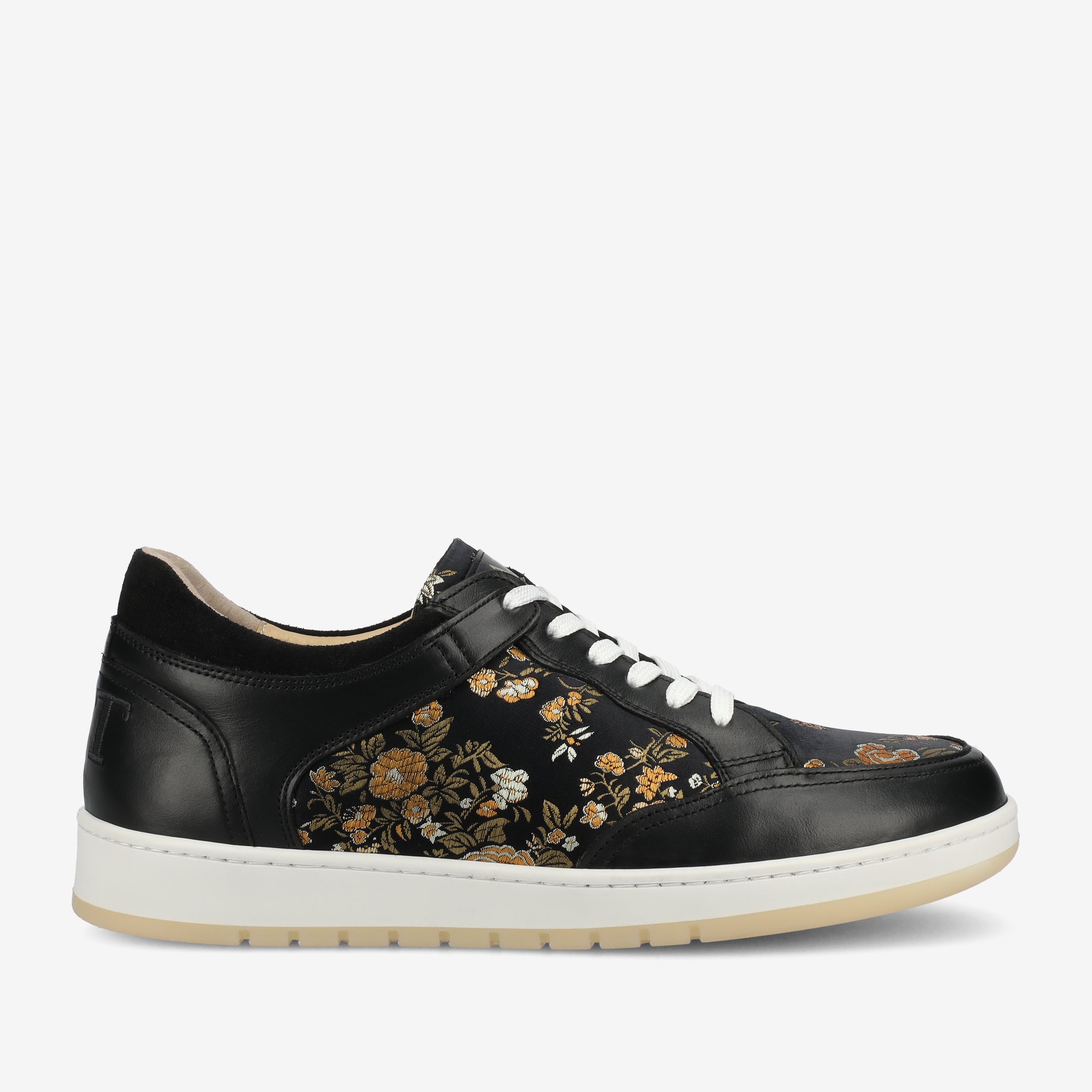 A black sneaker with white laces and a white sole, featuring a floral pattern with yellow and orange flowers on the sides.