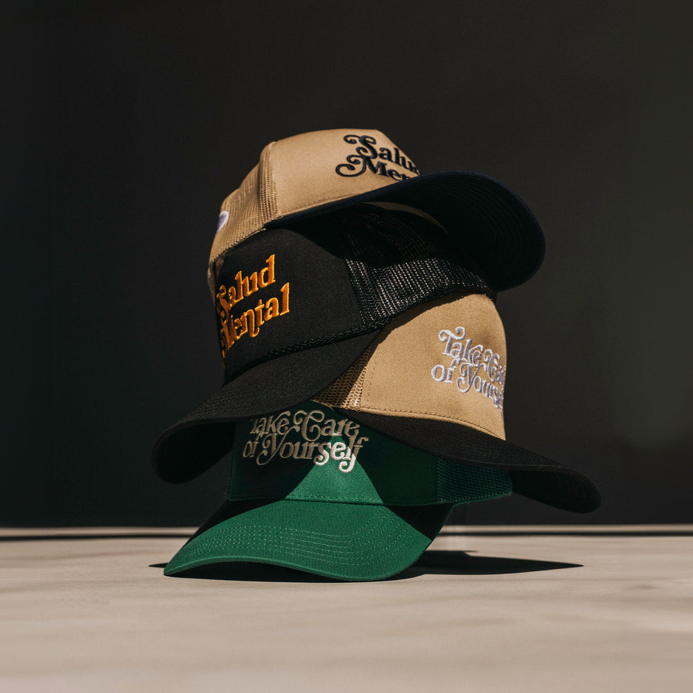 A stack of three trucker hats with embroidered text in various colors and designs.