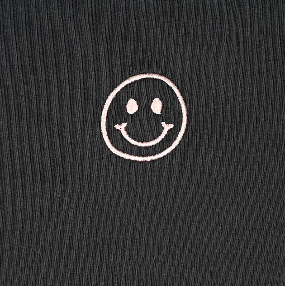 A simple, white smiley face design stitched on a dark fabric background.