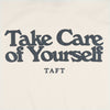 Off-white clothing with a bold black text reading Take Care of Yourself and a smaller TAFT below it.