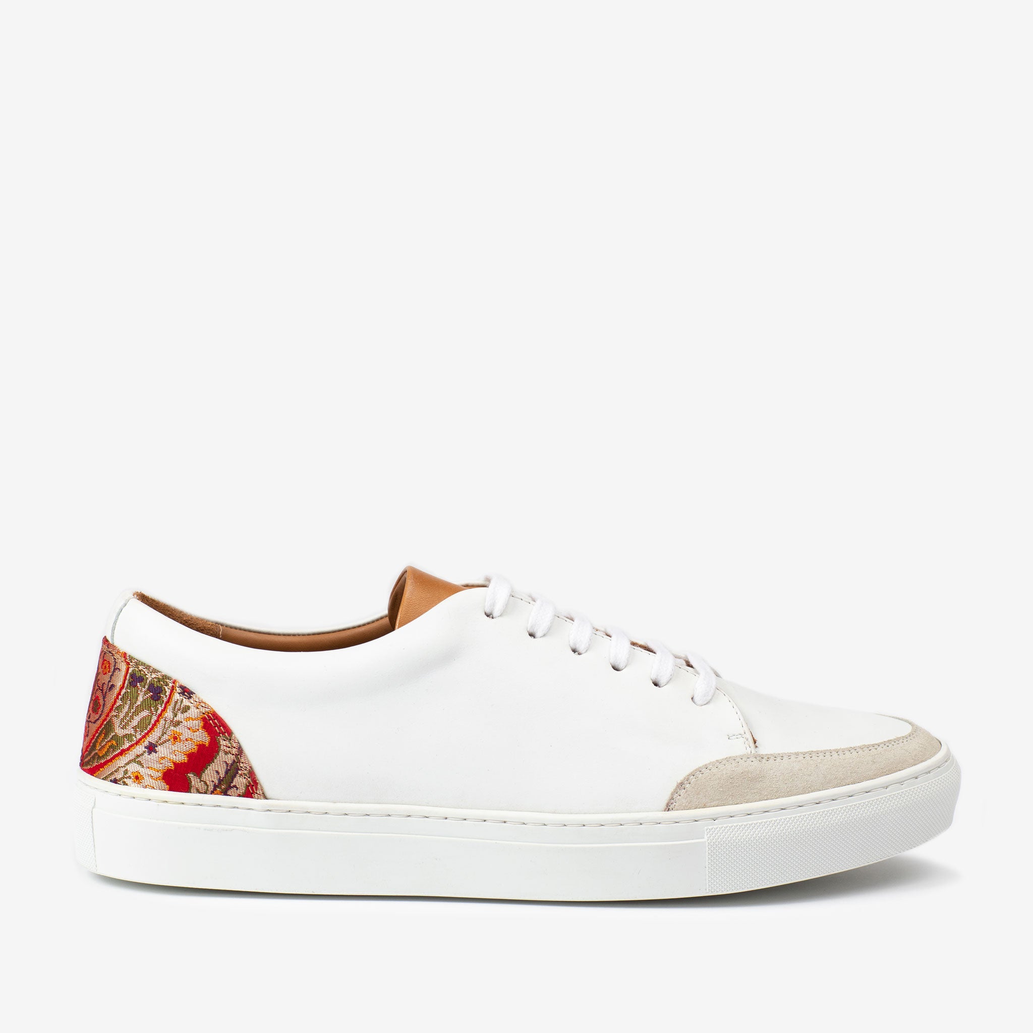 White low-top sneaker with a brown insole, white laces, beige toe cap, and patterned fabric detail on the heel counter, set against a plain white background.