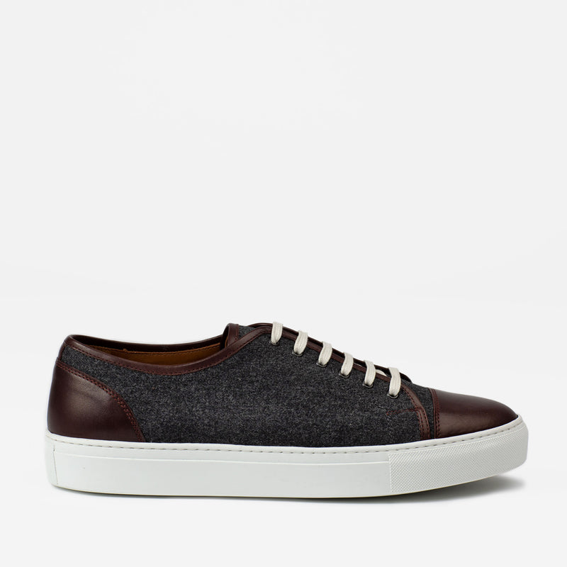 A dark gray and maroon leather low-top sneaker with a white rubber sole and white laces, photographed on a plain white background.