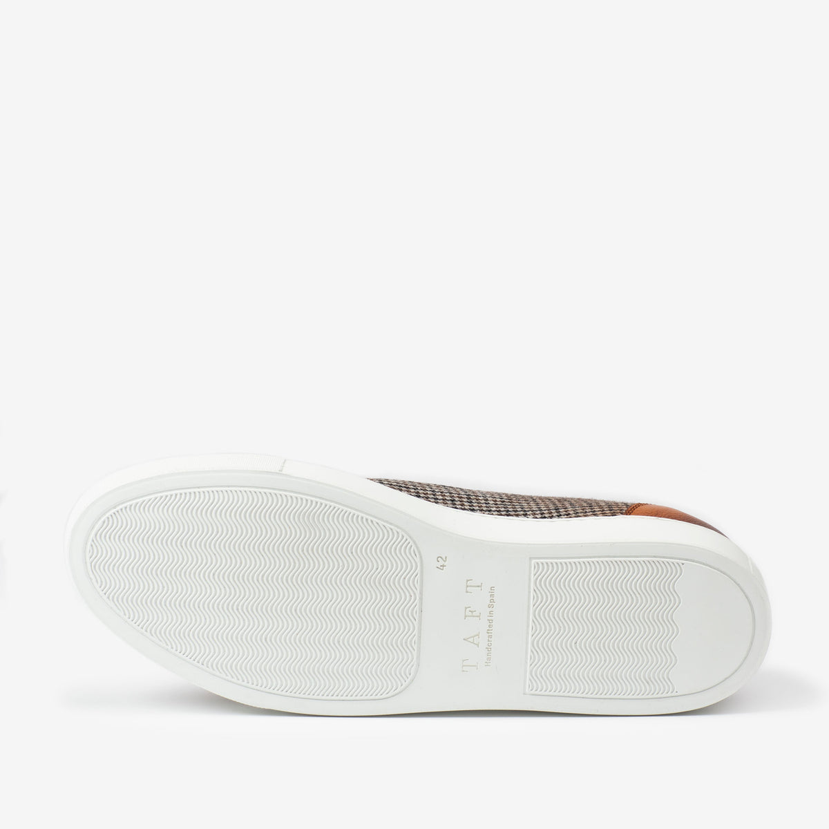 Bottom view of a single casual shoe with a white sole featuring wavy grooves and the brand name TAFT.