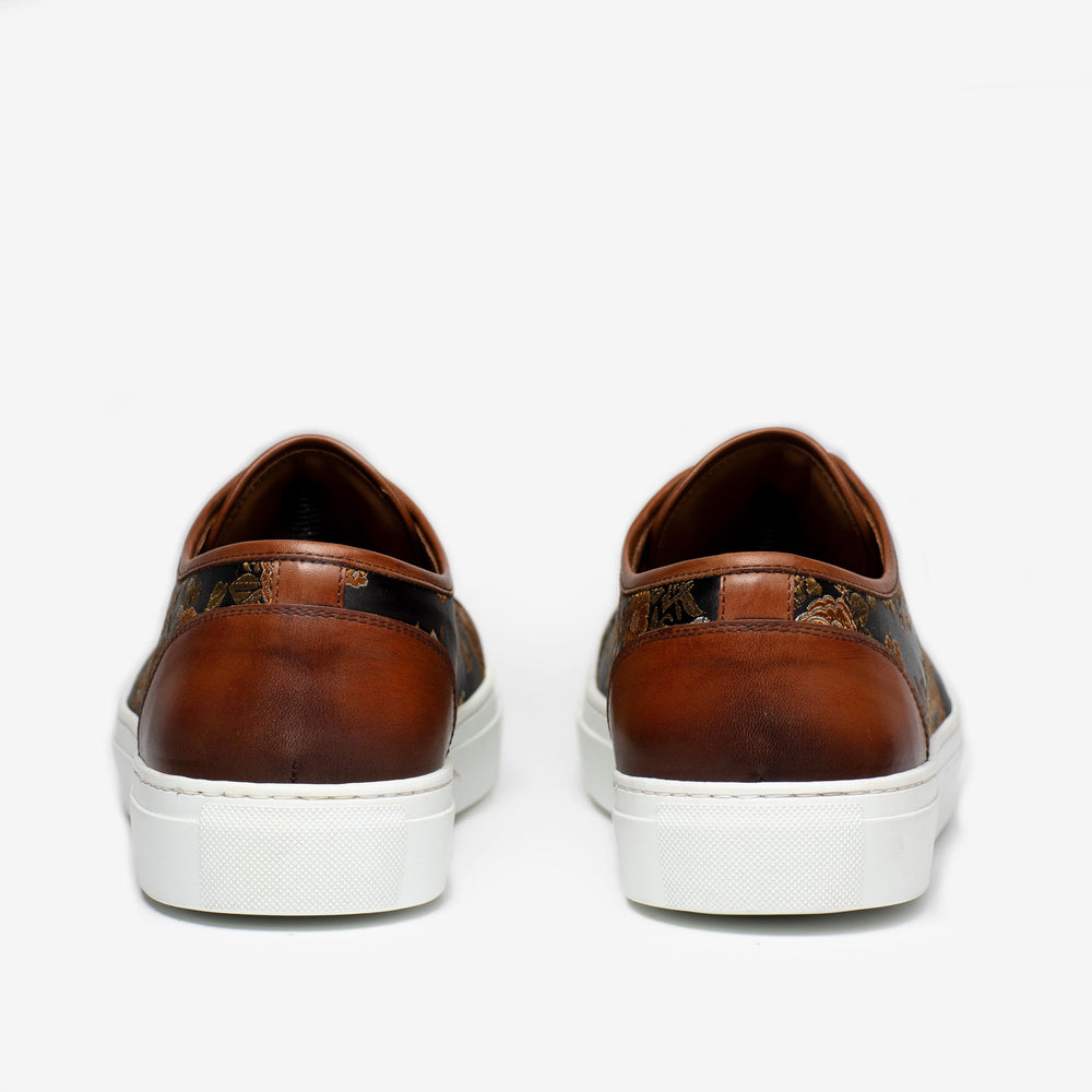 A pair of brown leather sneakers with white soles, viewed from the back against a white background.