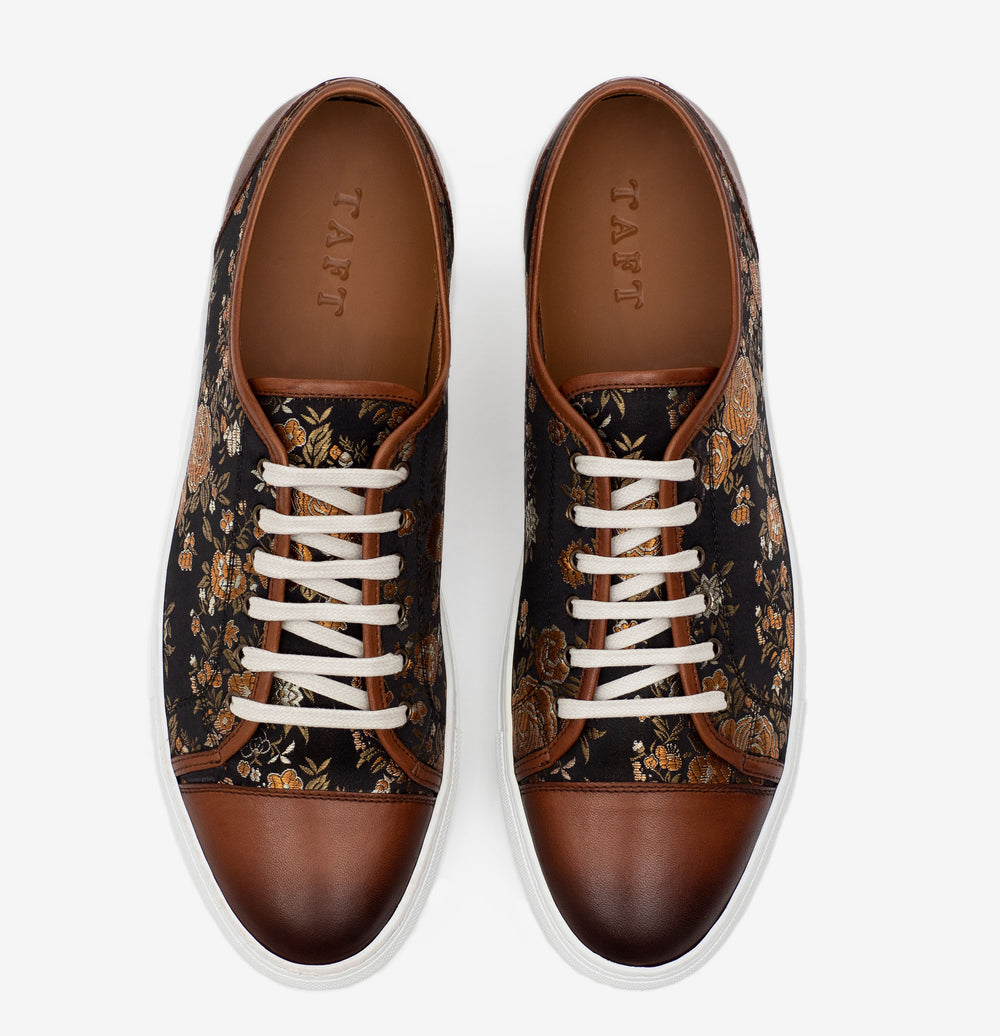 A pair of brown and black floral patterned sneakers with white laces, viewed from above.