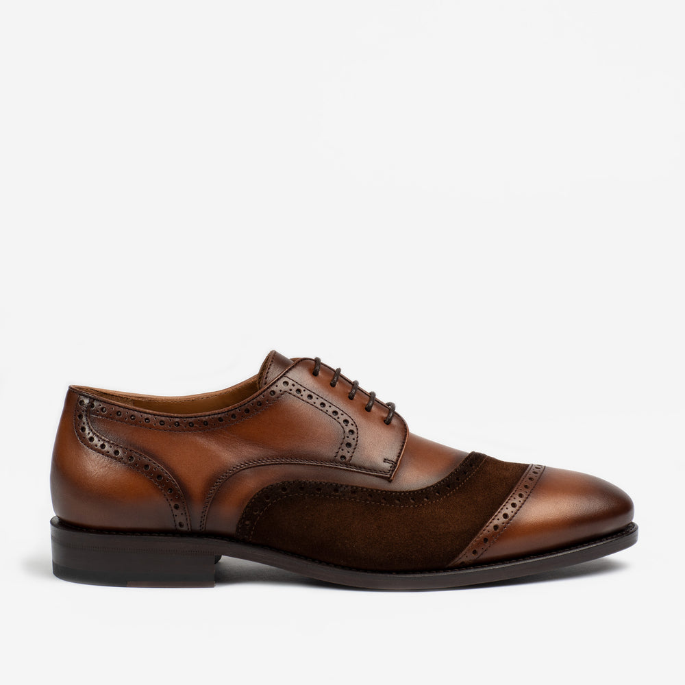 A brown leather and suede oxford shoe with brogue detailing and black laces, shown in a side profile against a white background.