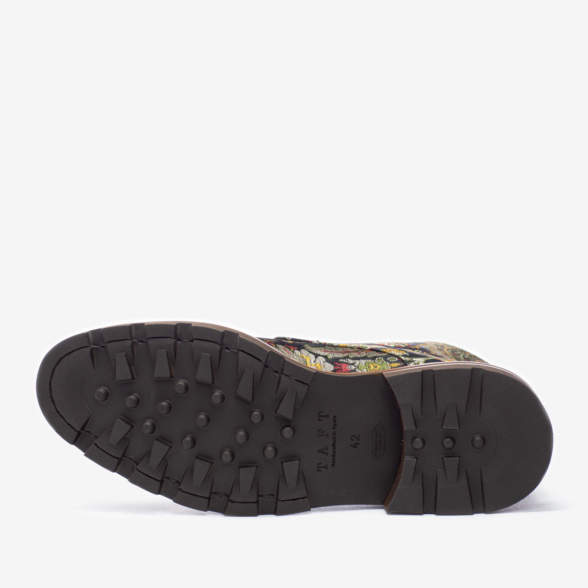 The image shows the sole of a shoe featuring a treaded, black rubber bottom. The brand name TAFT is visible on the sole. The upper part of the shoe has a colorful pattern.