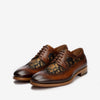 A pair of brown leather dress shoes with intricate floral embroidery and detailed broguing on a white background.