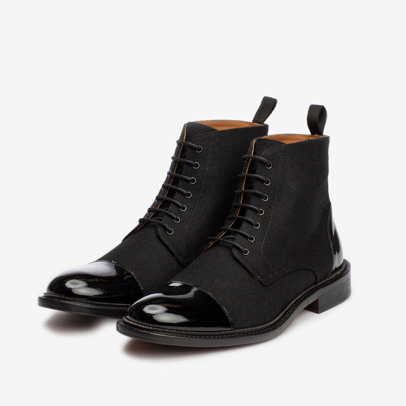 A pair of black lace-up formal boots with a polished, shiny toe and a pull tab at the back, set against a plain white background.