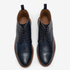 A pair of navy blue leather lace-up ankle boots with brown detailing and tan interior, viewed from above.