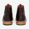 Rear view of a pair of dark brown leather ankle boots with wooden soles and purple pull tabs.