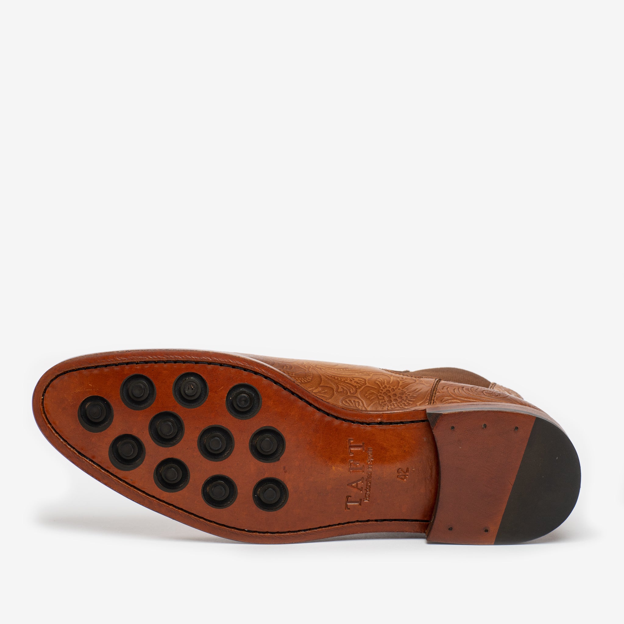 The image shows the sole of a brown leather shoe with black rubber studs and visible stitching, displaying the brand name TAFT.