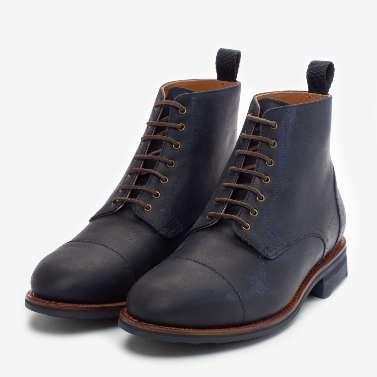 A pair of dark blue leather lace-up boots with brown soles and pull tabs on a white background.