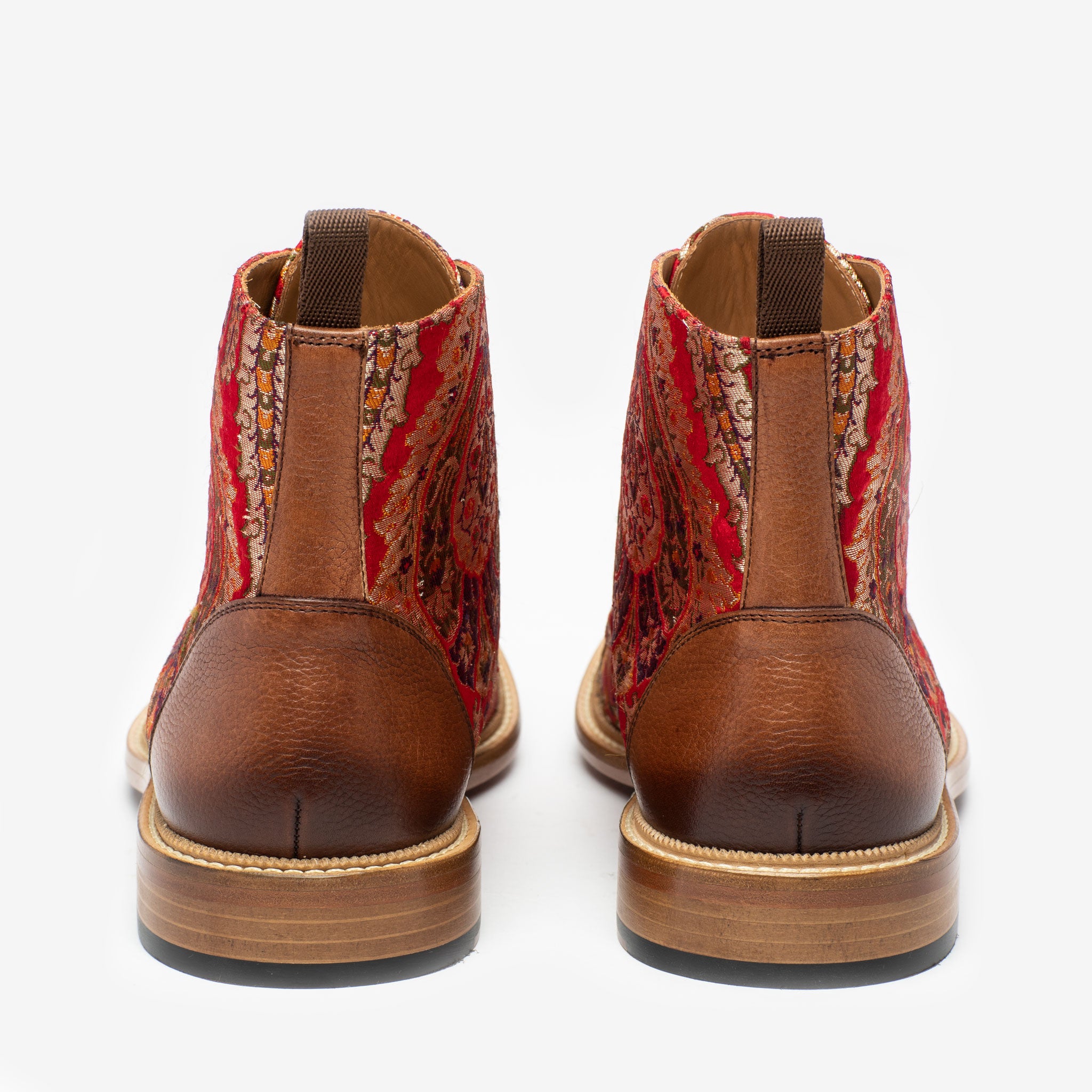 Rear view of two brown and red patterned ankle boots with a wooden sole against a white background.