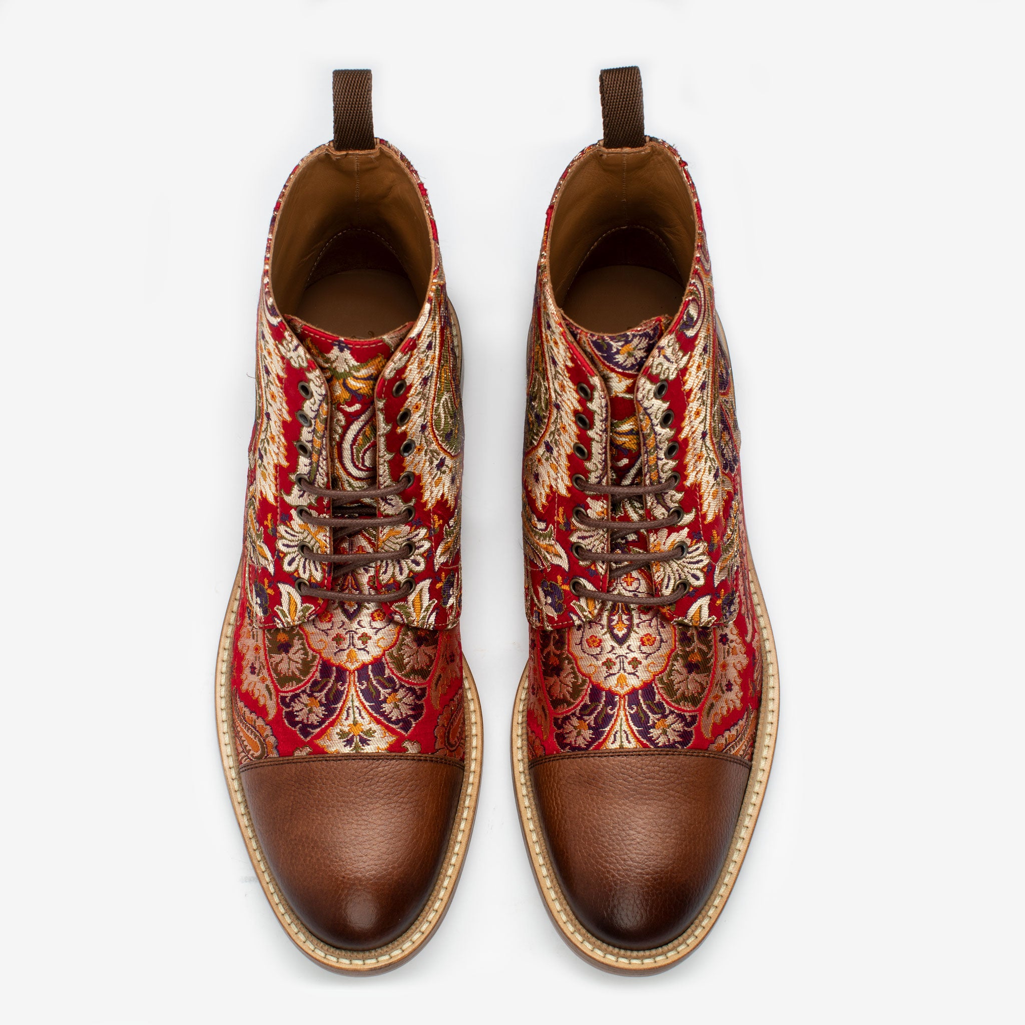 Pair of high-top shoes with intricate red, orange, and gold floral patterns, brown leather toe caps, and beige soles, viewed from above.