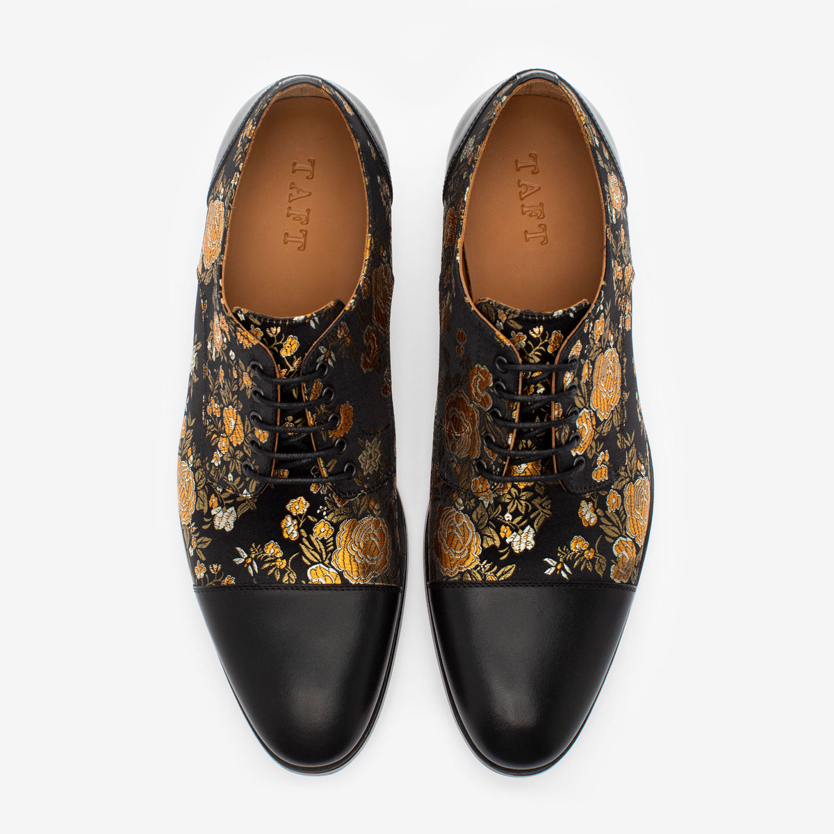 Pair of black leather lace-up dress shoes with gold and silver floral embroidery on a white background.