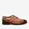 A brown and red brogue shoe with ornate paisley patterns and detailed embroidery on the sides.