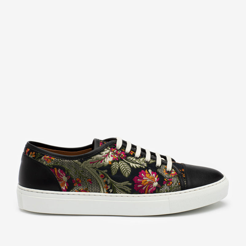 A stylish black sneaker with floral embroidery on the sides, white laces, and a white rubber sole.