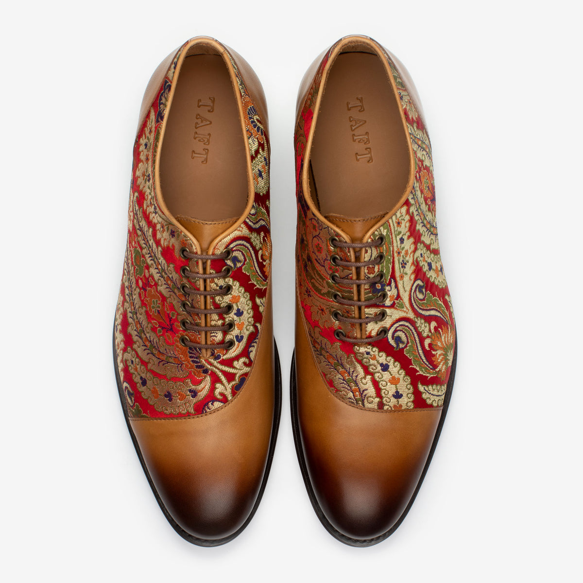 A pair of men's dress shoes featuring intricate red and gold paisley patterns on the sides and smooth brown leather on the toes and laces, viewed from above.