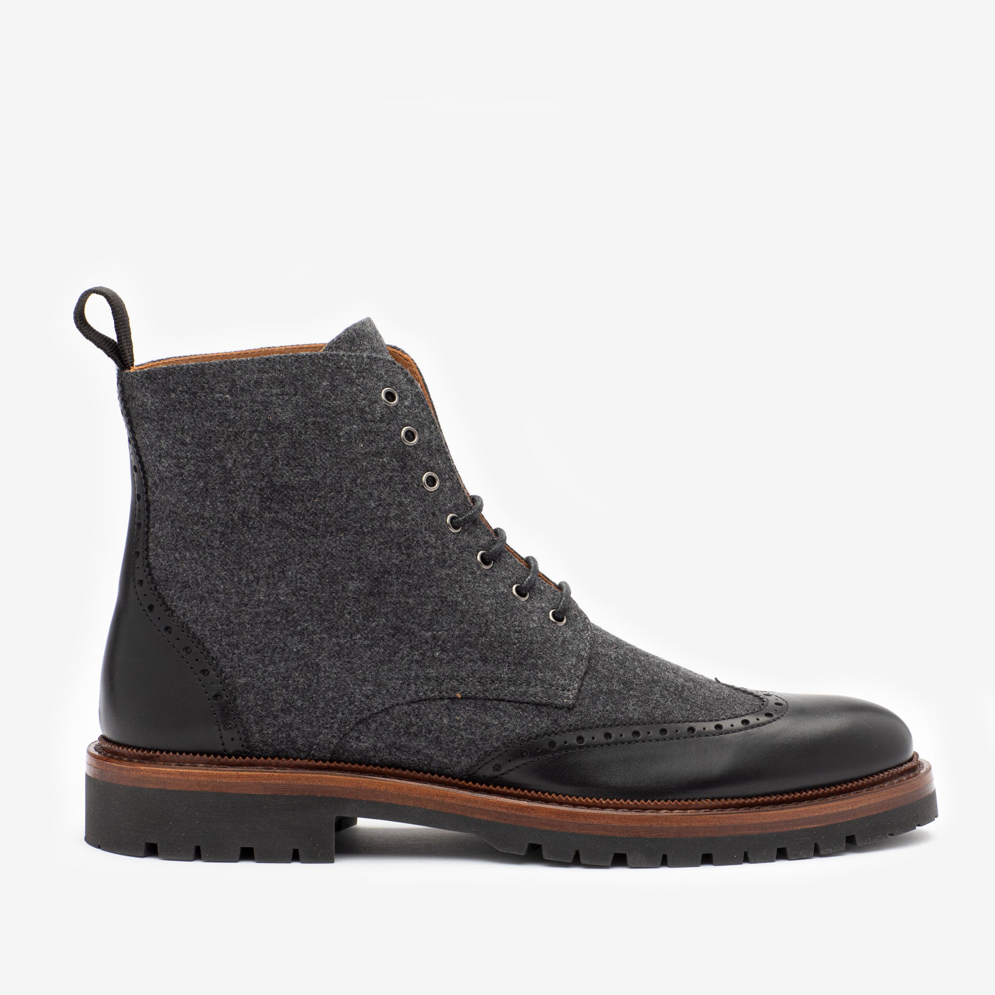 A black and gray lace-up boot featuring brogue detailing, a leather toe cap, fabric upper, and a sturdy sole with a pull tab at the back.