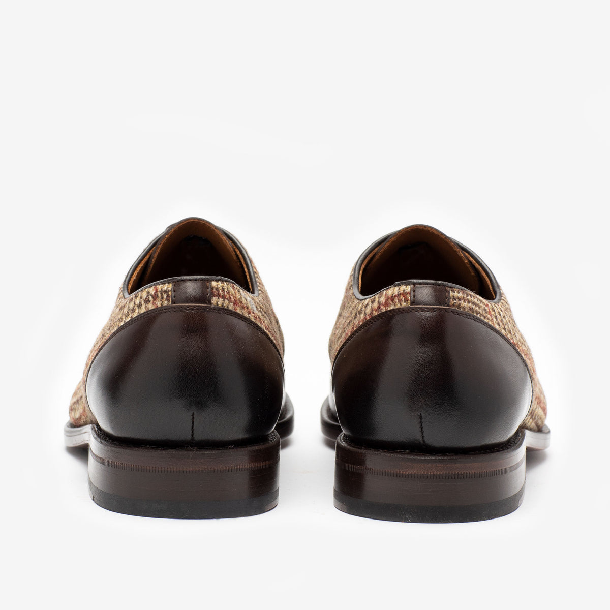 Rear view of a pair of men's dress shoes featuring brown leather and houndstooth fabric detailing.