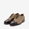 A pair of brown and tan houndstooth-patterned men's dress shoes with black leather toe caps and laces, set against a plain white background.