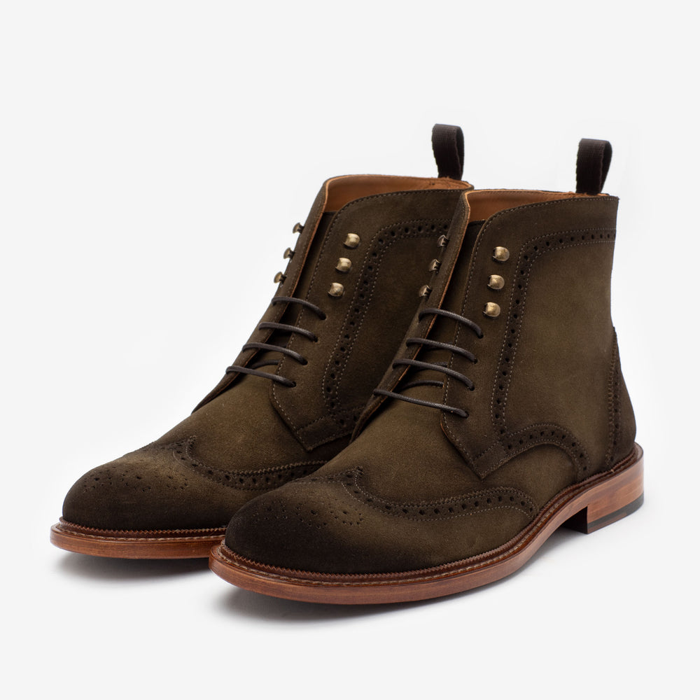 A pair of brown suede brogue boots with decorative perforations, laces, metal eyelets, and wooden soles, placed side by side on a plain white background.