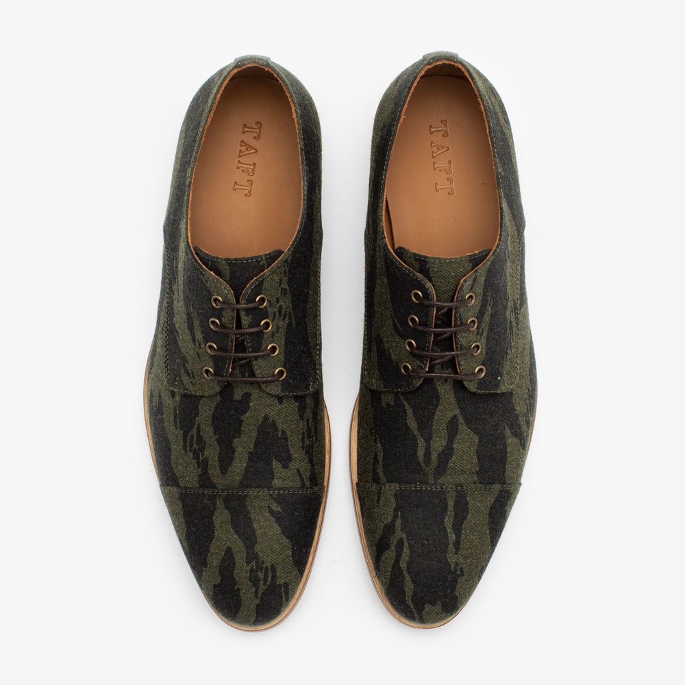 A pair of camouflage-patterned dress shoes with brown laces and a tan lining, viewed from above.