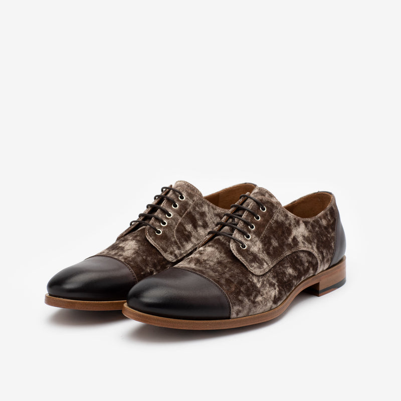 Pair of men's dress shoes with brown velvet-like texture on the body, black leather cap toe, brown sole, and black laces against a white background.