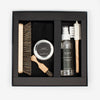 A shoe care kit containing a large brush, a small brush, shoe shampoo spray, polish, and a cloth, all arranged in a black box.