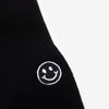 Close-up of a black fabric with a small white embroidered smiley face.