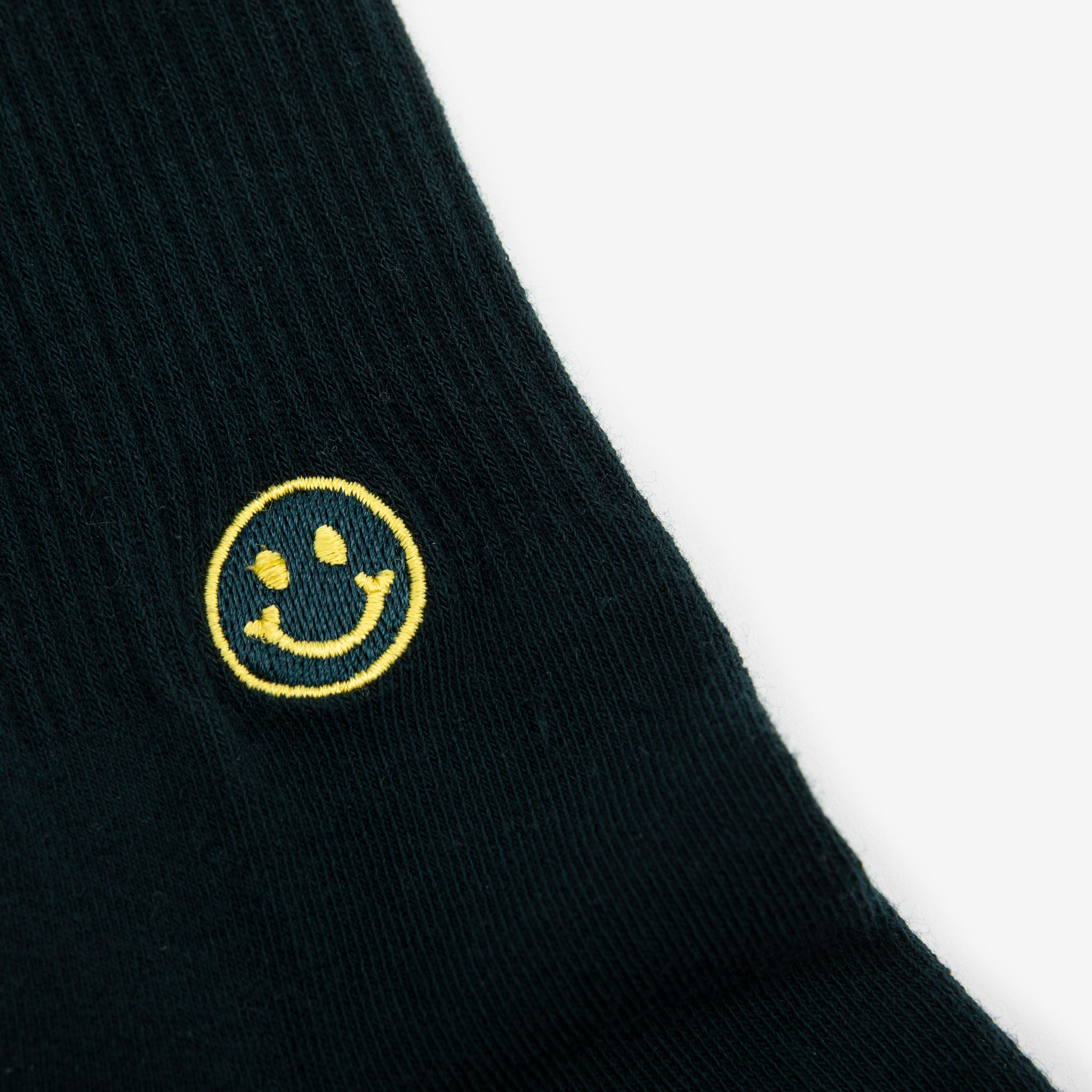 Dark green sock with a small, yellow embroidered smiley face near the top.