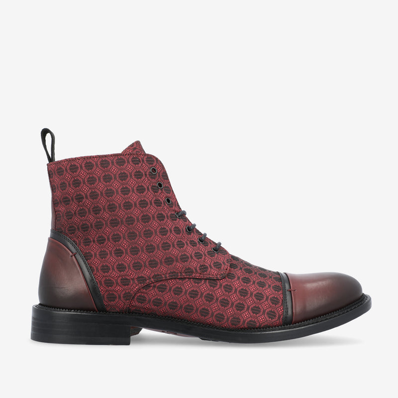 A red leather boot with a black sole and patterned upper, featuring a pull tab at the back and lace-up closure.