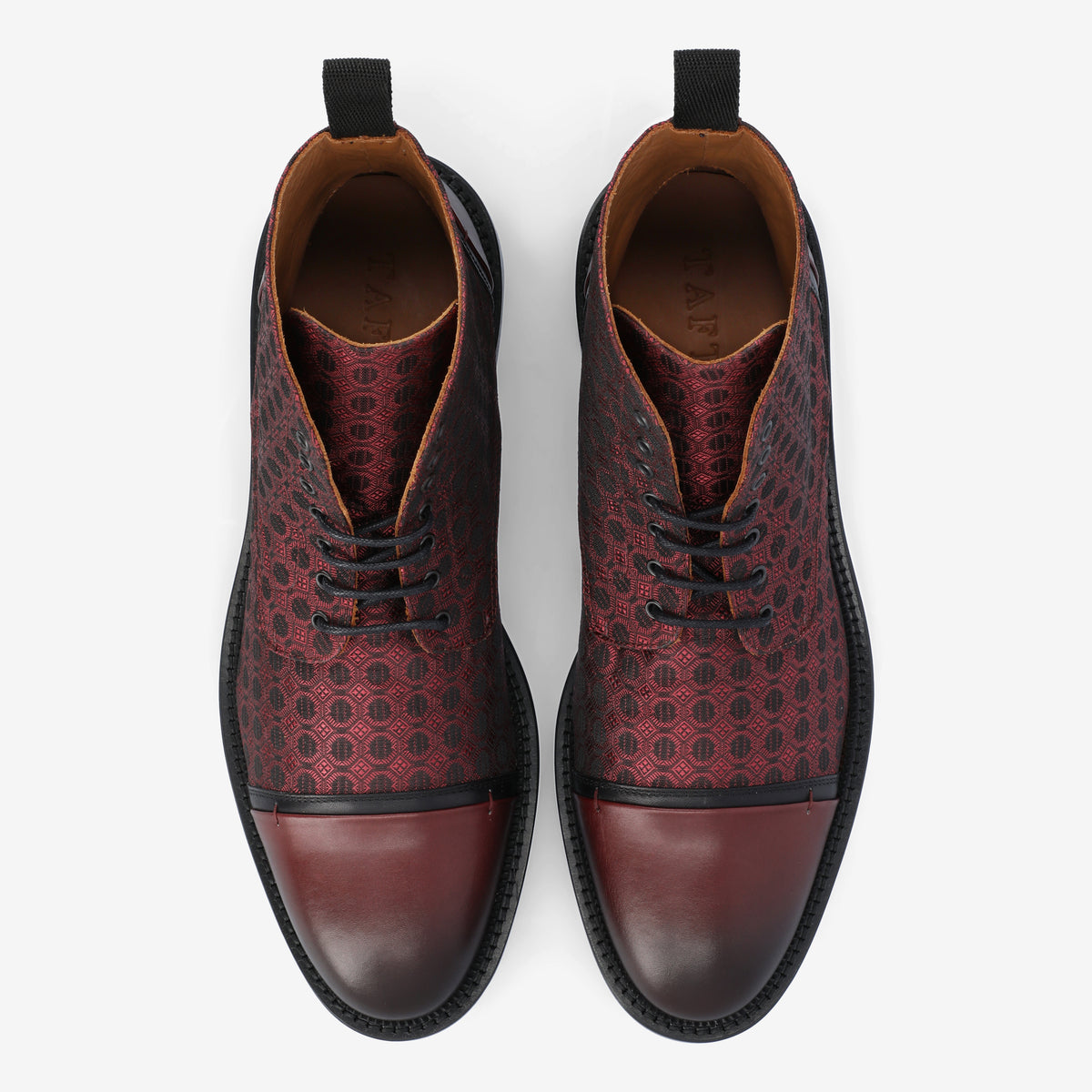 Top view of a pair of red and black patterned leather dress shoes with black laces and a black outsole.