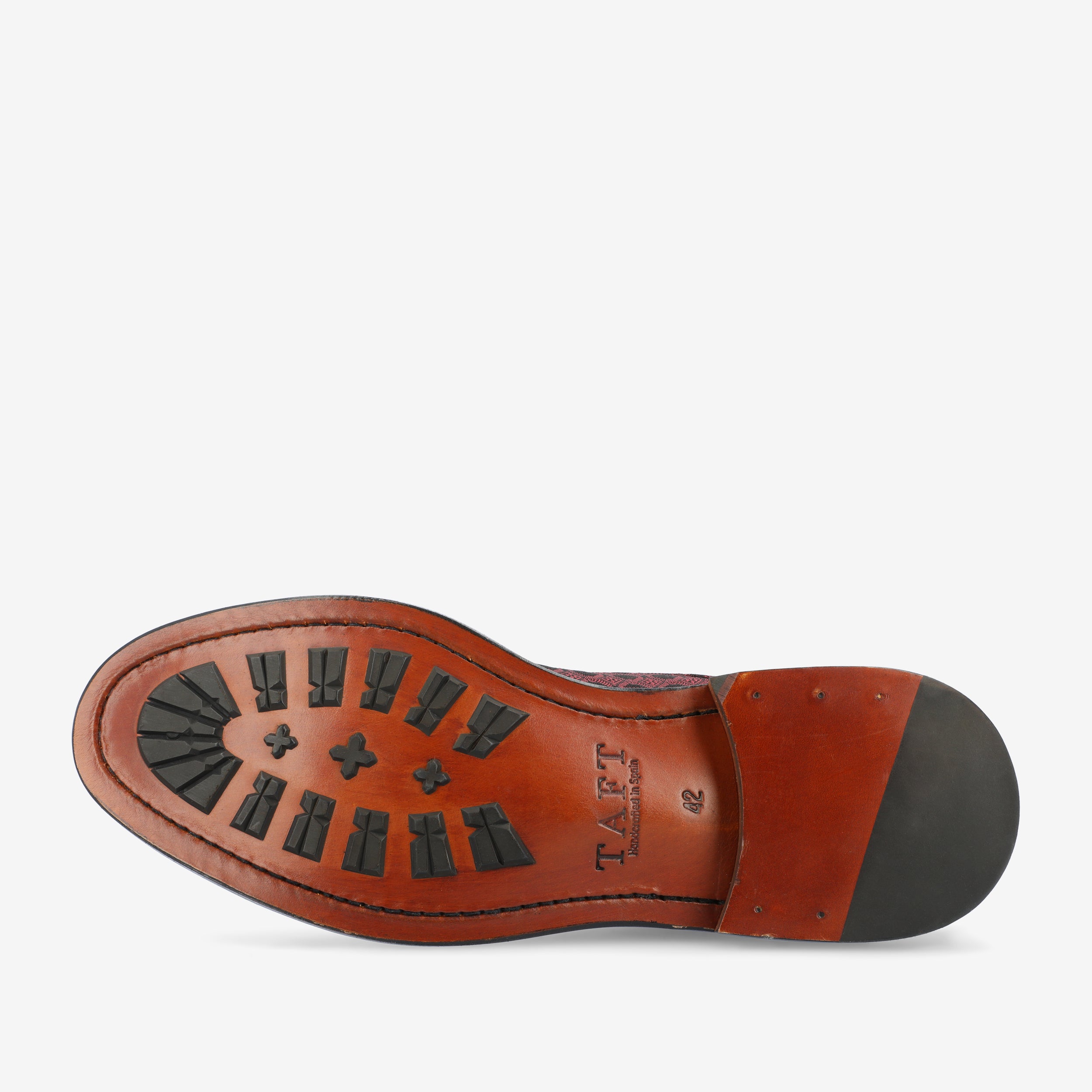 Bottom view of a brown leather shoe showing a rubber traction pattern and the engraved brand TAFT.