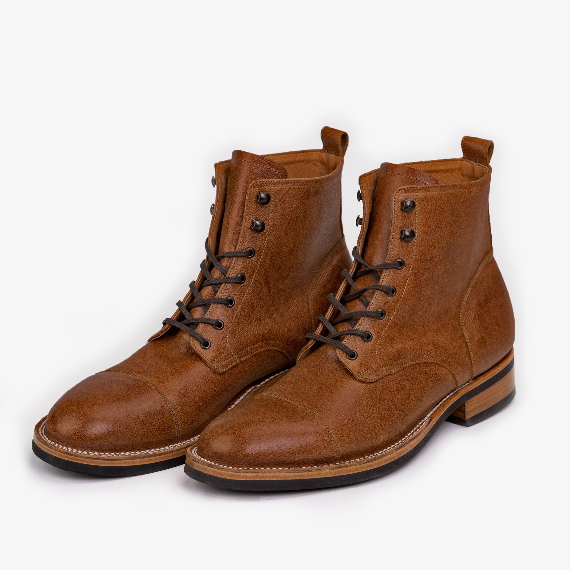 A pair of brown leather lace-up boots with black outsoles and tan midsoles, positioned side by side on a white background.