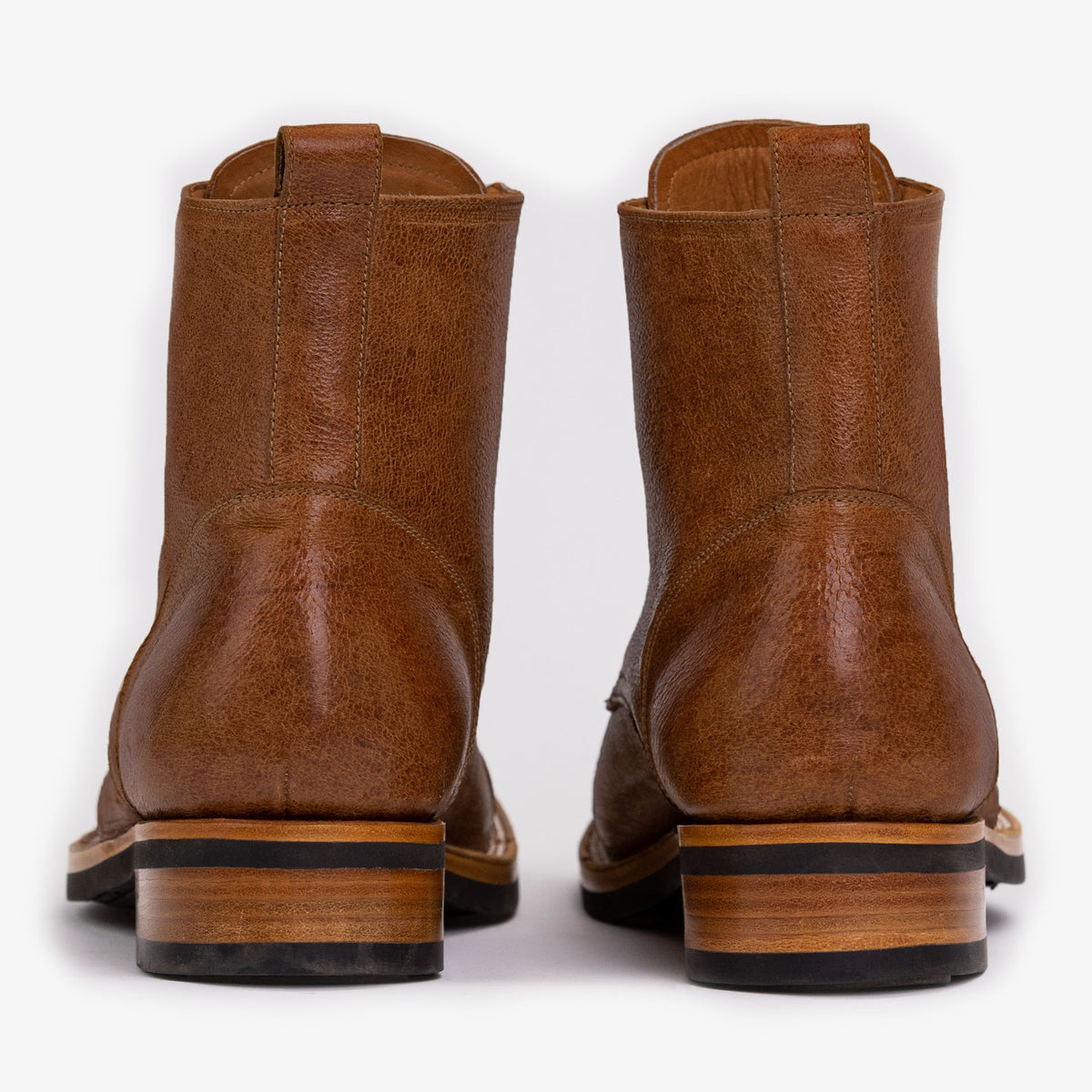 Rear view of a pair of brown leather ankle boots with stacked wooden heels and pull tabs.