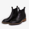 Pair of black leather Chelsea boots with elastic side panels and wooden soles, viewed from a slight angle against a white background.