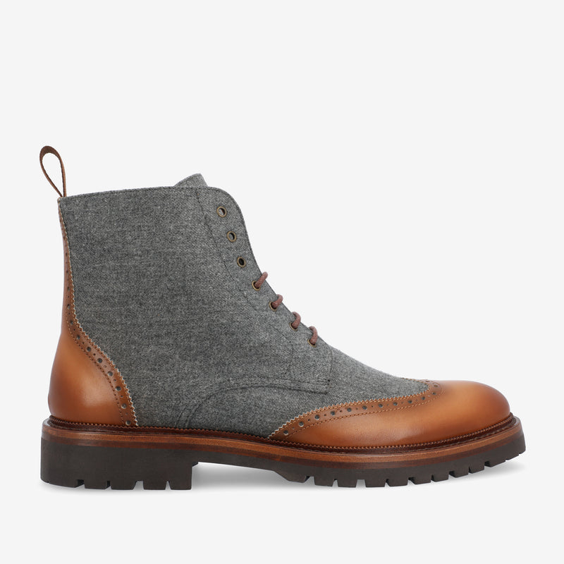 A gray wool and brown leather lace-up boot with brogue detailing and a thick rubber sole.