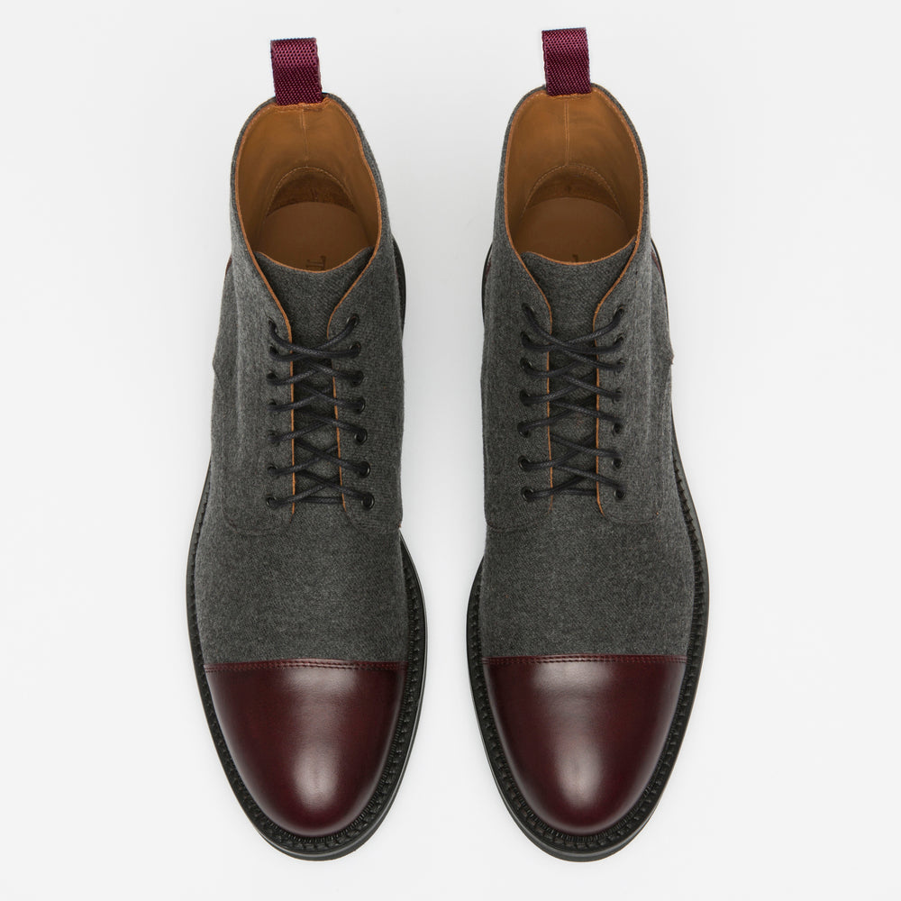 A pair of men's dress boots with dark grey fabric and burgundy leather cap-toes, featuring black laces and purple pull tabs on the heels, displayed on a white background.